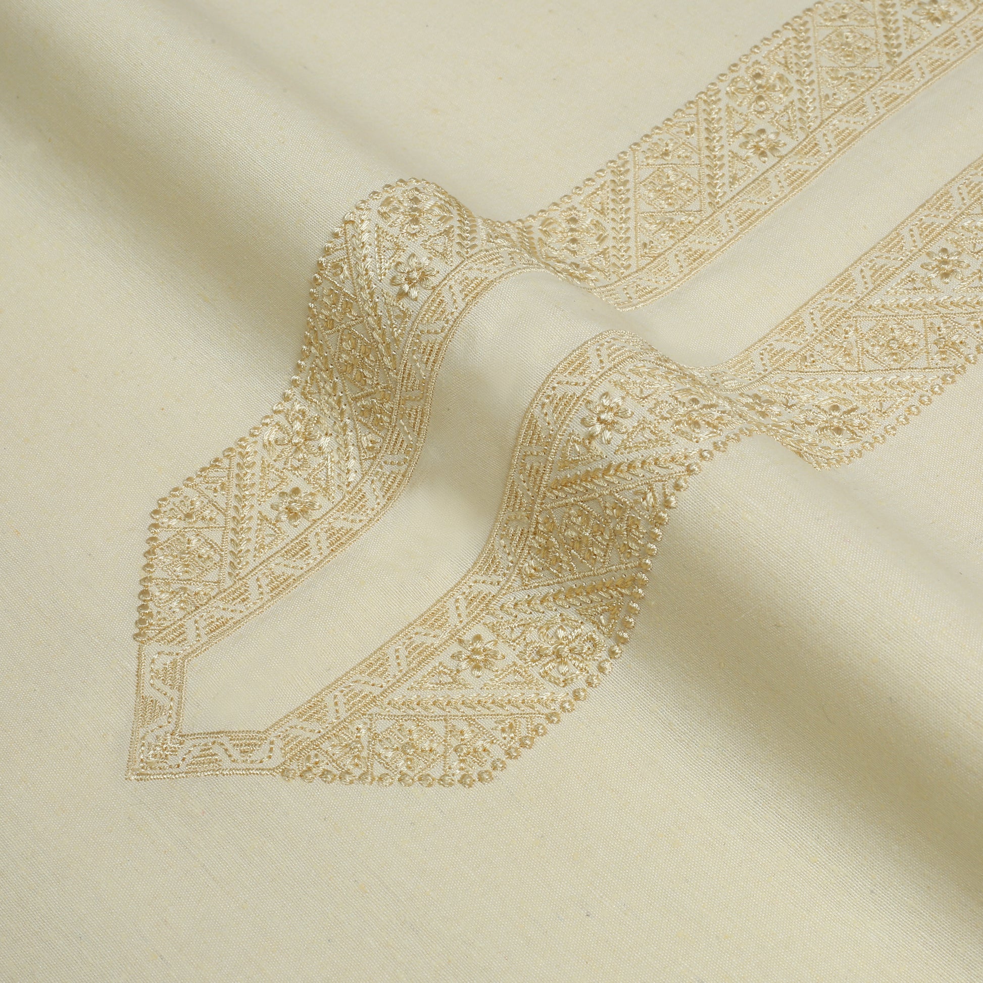 Close-up of beige fabric with intricate gold embroidery